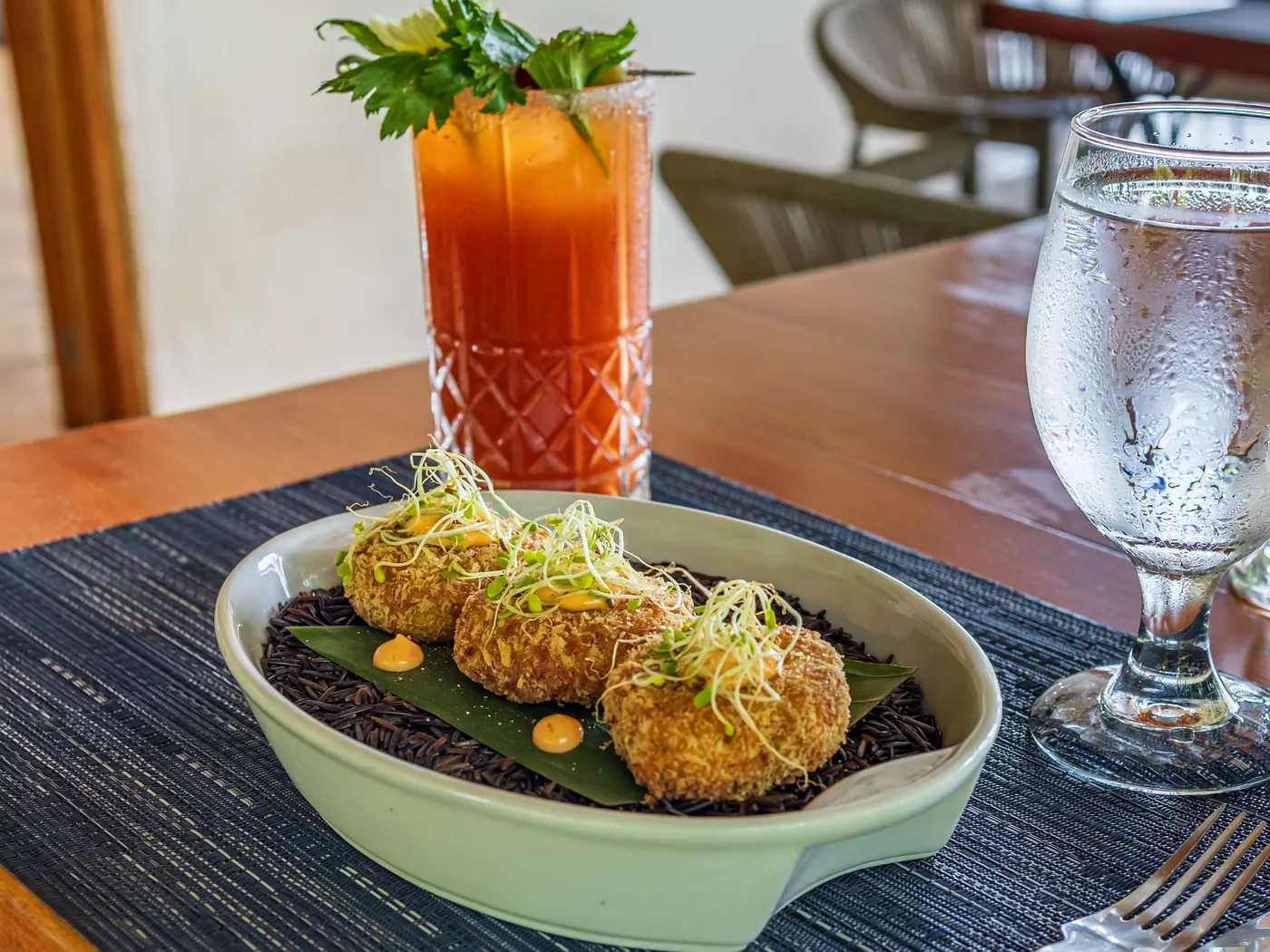 Croquetas crujientes sobre arroz negro con un cóctel tropical en Castillo's Kitchen