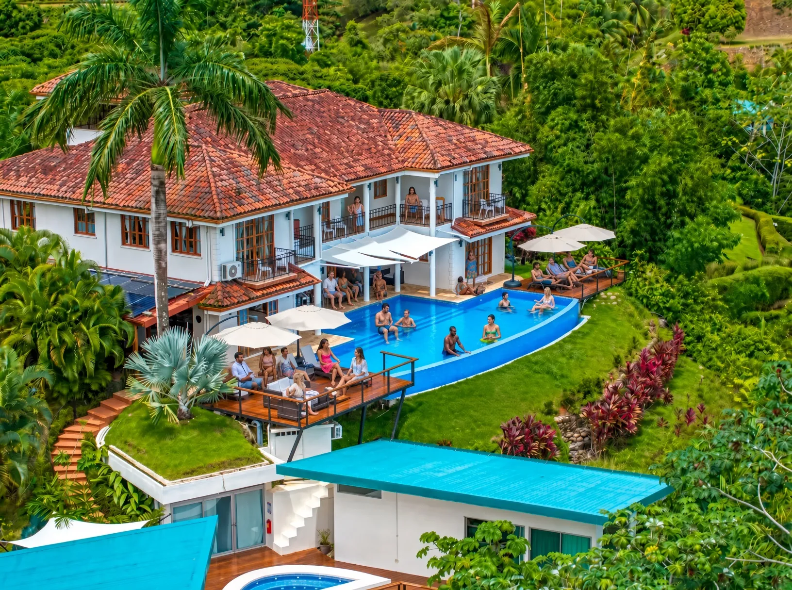 Aerial view of El Castillo's pool deck and terraces with guests, surrounded by jungle