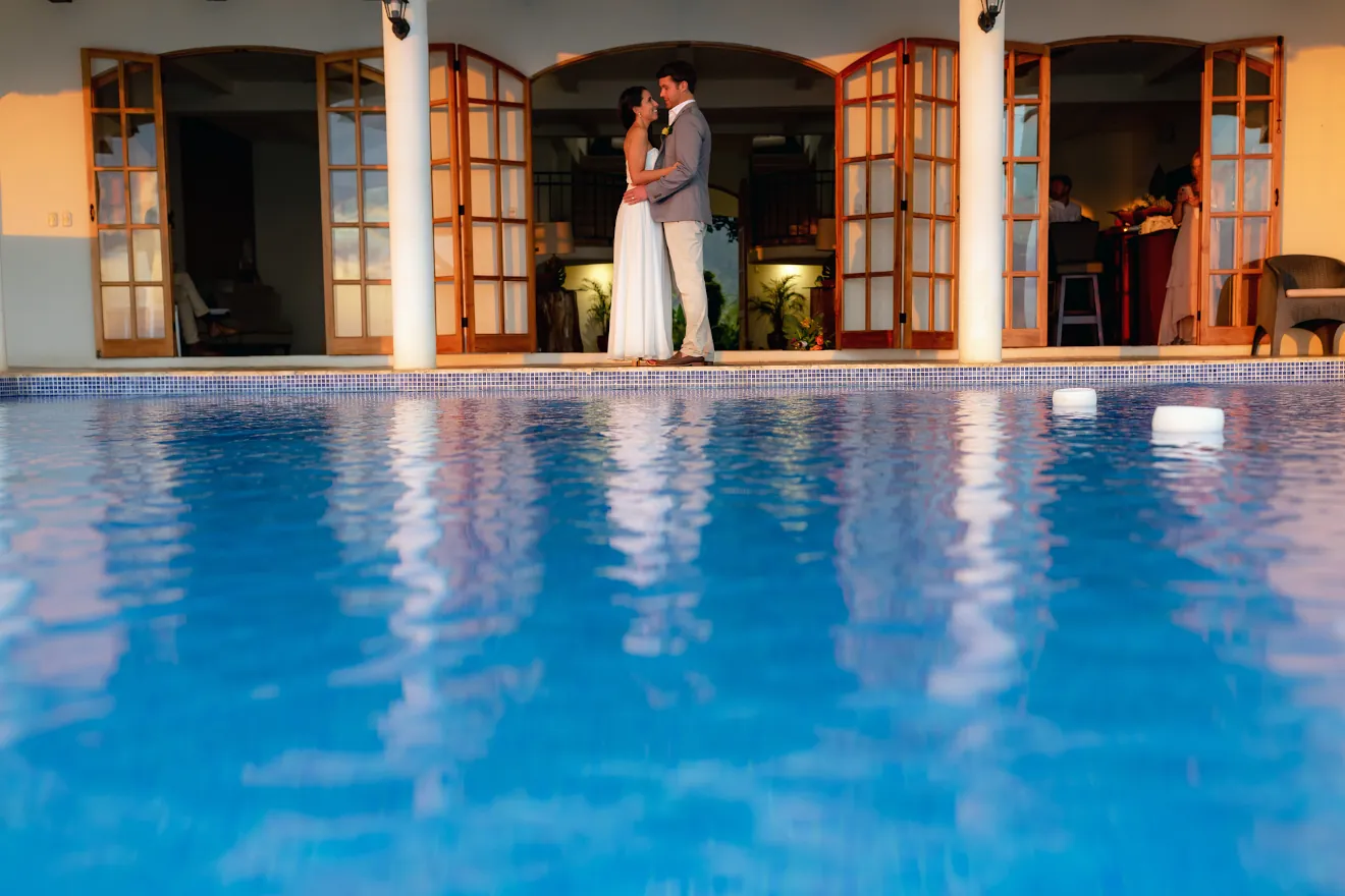 Wedding couple beside the lit infinity pool at dusk